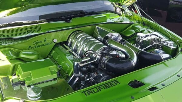 The engine of a green car parked in a lot