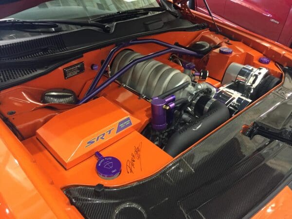 The engine compartment of an orange sports car