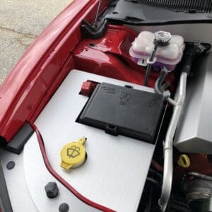 The engine compartment of a red car with its hood open