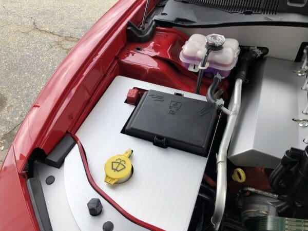 The engine compartment of a red car with its hood open