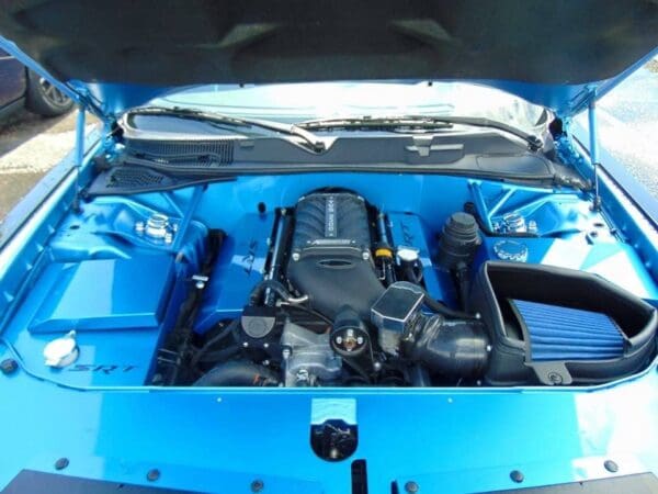 The engine compartment of a blue car with its hood open