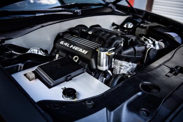 Close-up of a car engine featuring a 6.4L HEMI, with detailed components visible under the hood.
