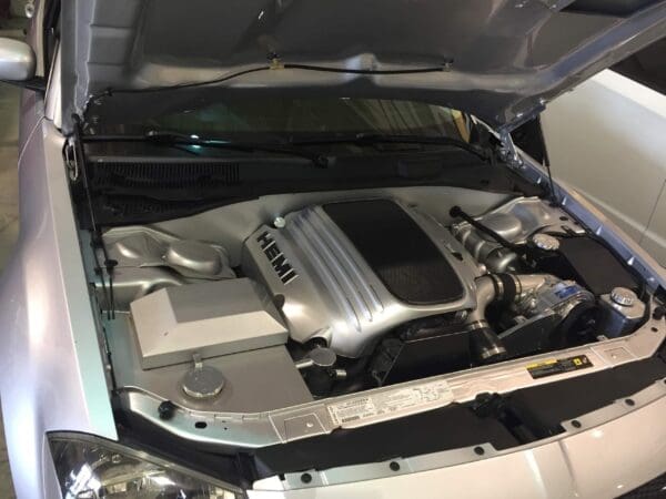 The engine compartment of a silver car is open, revealing a HEMI engine inside.