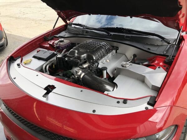 A red car with its hood open, showcasing a detailed view of the engine.