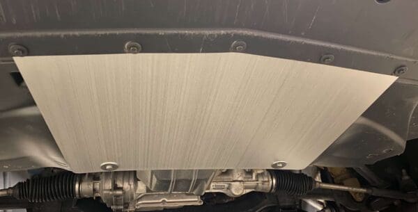 Close-up of a car's exhaust system, highlighting the metal shield and surrounding components.