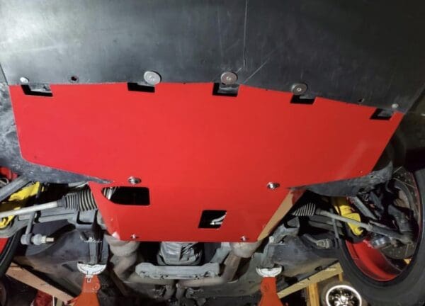 Red protective underbody panel installed on a car, viewed from below.