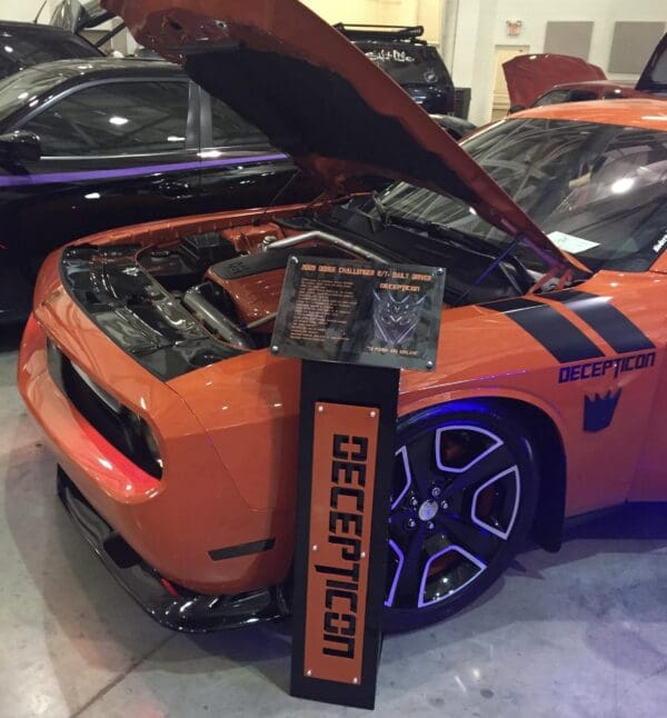 An orange sports car with its hood open