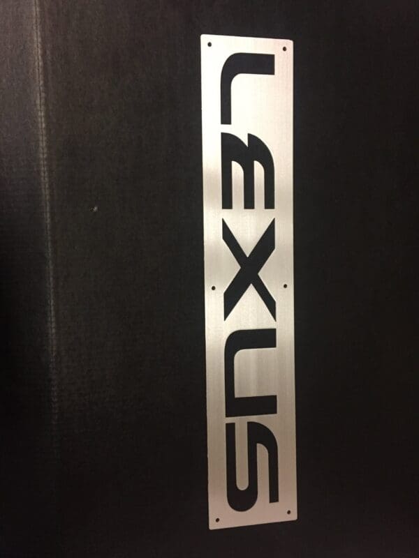 Metallic informational sign with the word "LEXUS" against a black background.