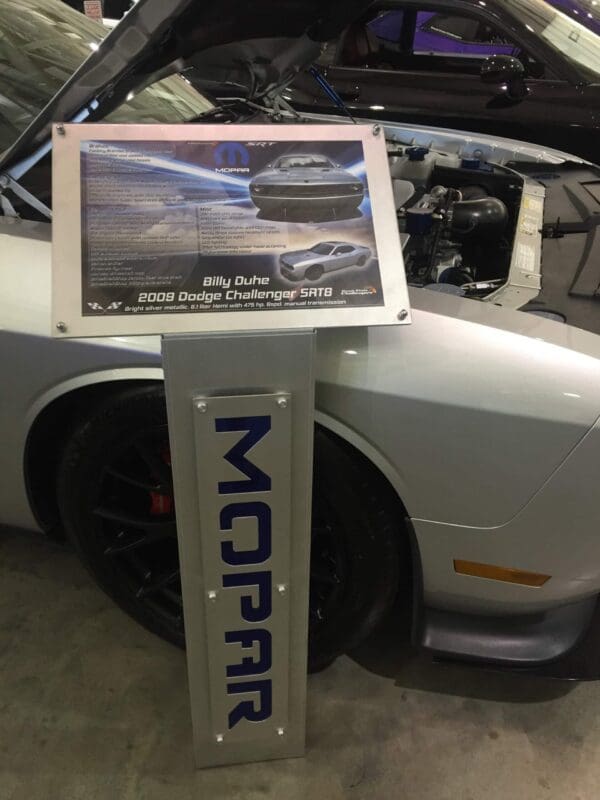 Display of a 2009 Dodge Challenger SRT8 with an open hood and Mopar sign.