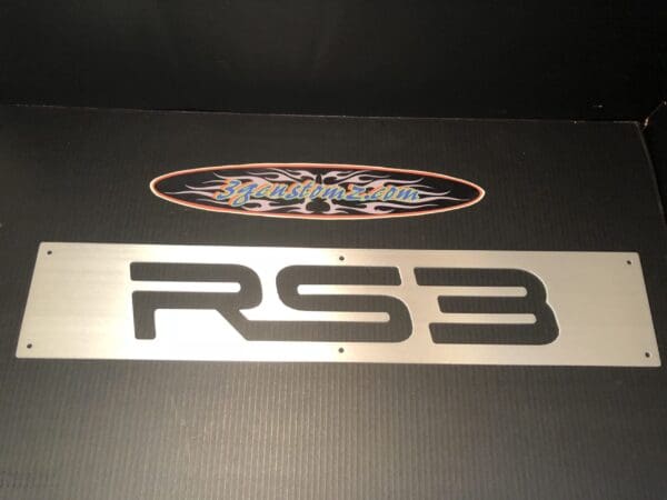 Metallic 'RS3' license plate on a textured black background.