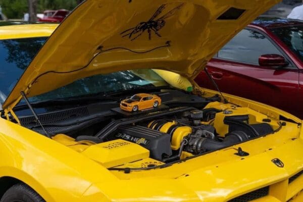 A yellow sports car with its hood open