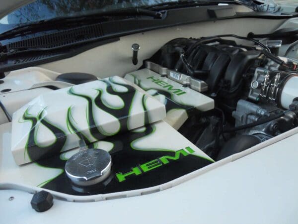 Car engine compartment with white and green design featuring "HEMI" and flame patterns.