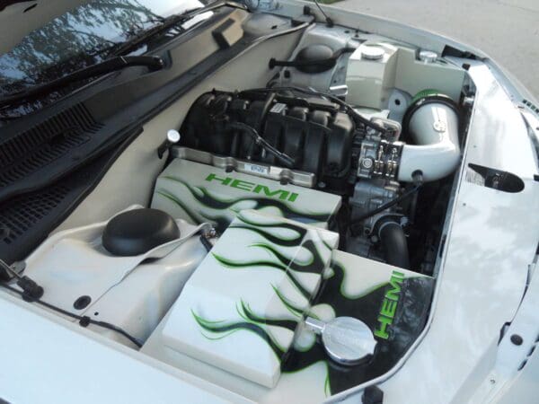 White car engine with custom "HEMI" design featuring green and black flame patterns.