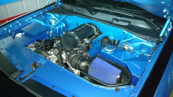 The engine compartment of a blue car with the hood up