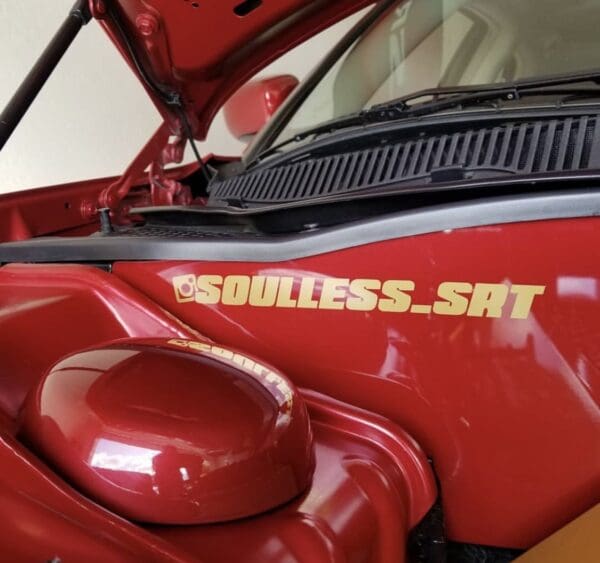 The hood of a red car with the word soulless sat on it