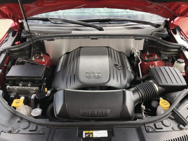 Car engine with hood open, showcasing a 5.7L V8 HEMI engine, surrounded by various components and fluid reservoirs.