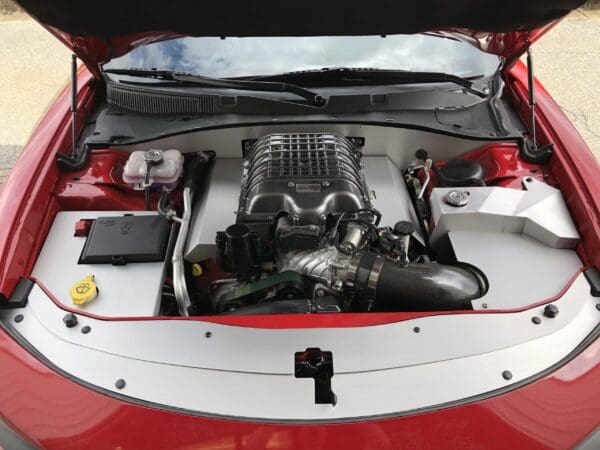 The engine of a red car with the hood open, showing detailed components and a clean layout.