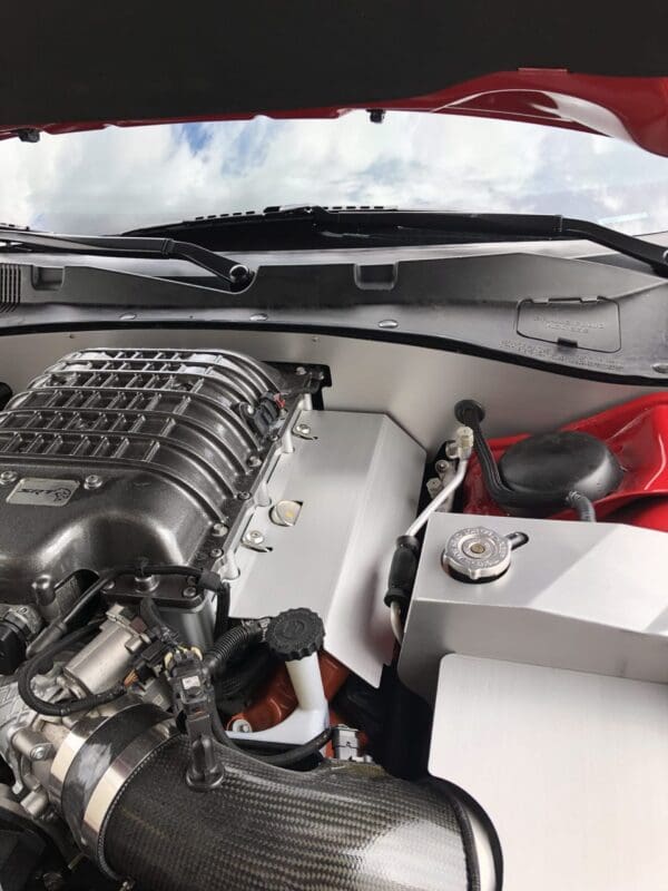 Close-up view of a car engine with visible components, including a carbon fiber air intake and metallic engine parts.