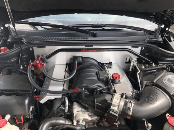 Car engine with hood open, featuring a Takeda air intake system and a Mishimoto oil catch can, showcasing performance upgrades.