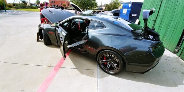 A car with its hood open parked in a parking lot