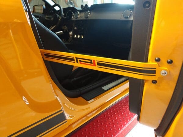 A close up of a yellow car door with a black stripe