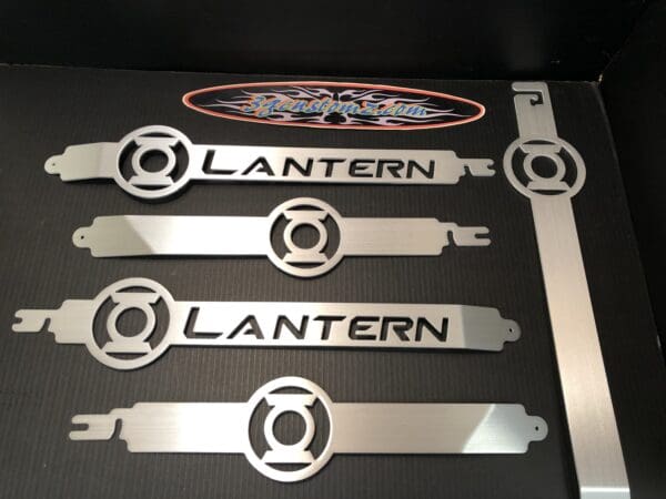 A set of four metal name plates on a black surface