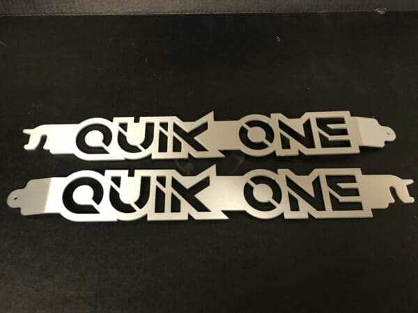 A pair of metal stickers that say'quik one quik one '