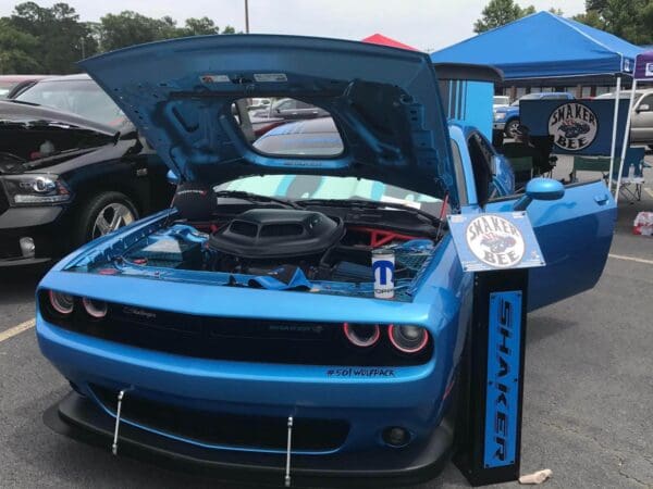 A blue car with its hood open in a parking lot