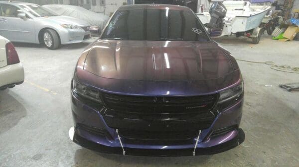 A purple car parked in a garage next to other cars