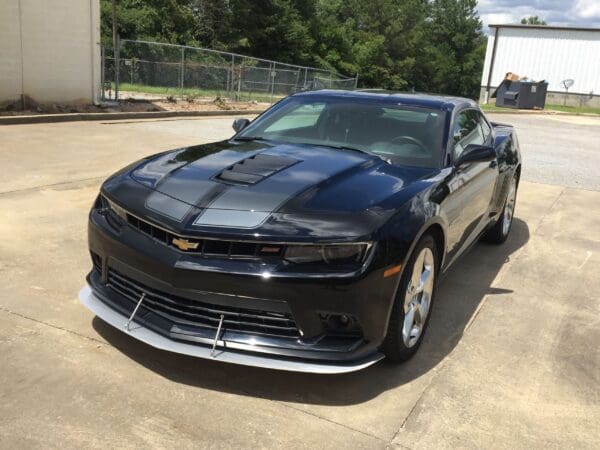 A black Chevrolet Camaro is parked in a parking lot, showcasing its sleek design and sporty features.