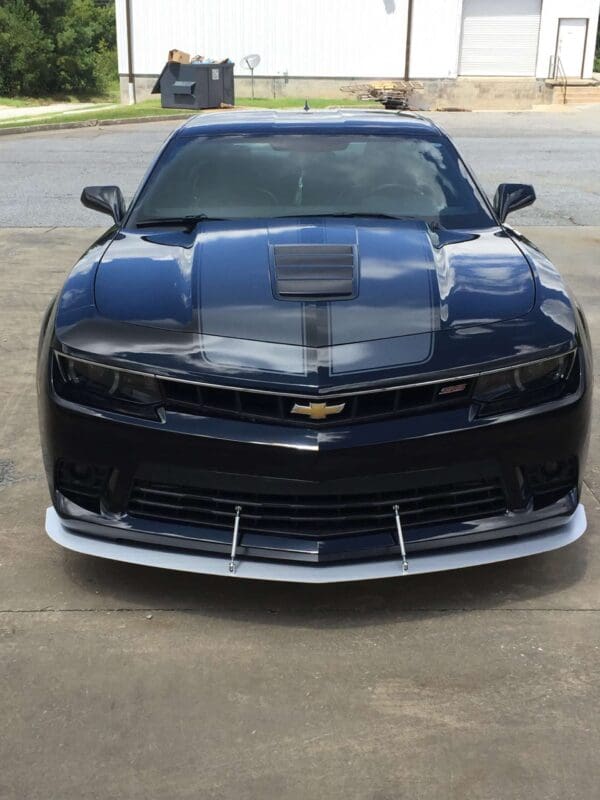 A black Chevrolet Camaro is parked in a parking lot, showcasing its sleek design and front grille.