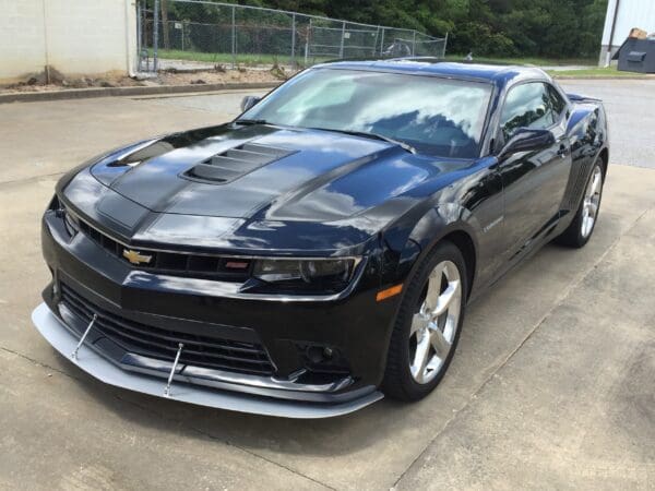 A black Chevrolet Camaro parked in a lot, featuring a sleek design and shiny chrome wheels.