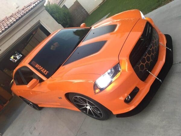 An orange sports car parked in front of a house