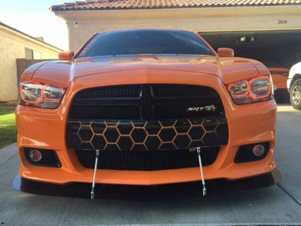 An orange dodge charger parked in front of a house