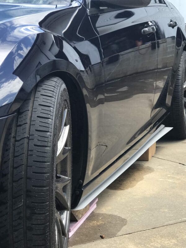 A black car parked on the roadside, showcasing its polished exterior and detailed tire tread.