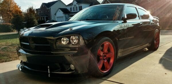 A black dodge charger parked in front of a house