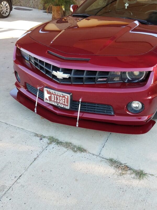A red Chevrolet Camaro with a custom license plate reading "D13SEL" is parked in a driveway.