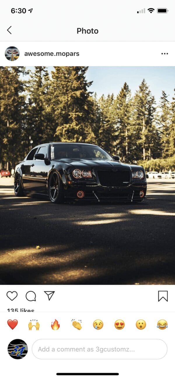 A black car parked in a parking lot next to trees