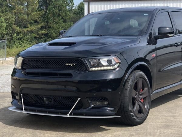 A black Dodge SUV parked in front of a building, showcasing its sleek design and sporty grille.