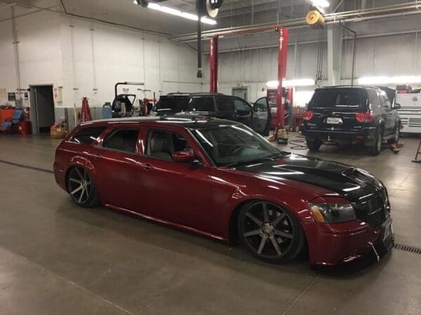 A red car parked in a garage next to other cars