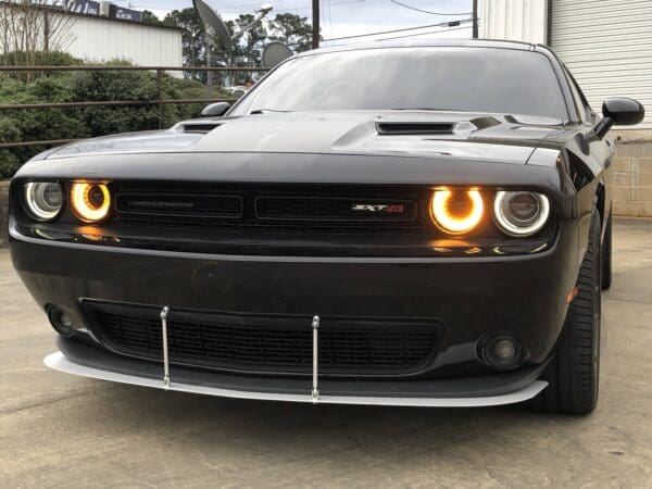 The front of a black car with its lights on