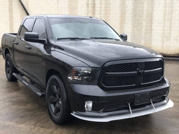 A black truck parked in a lot, featuring a sleek design and dark-tinted windows.