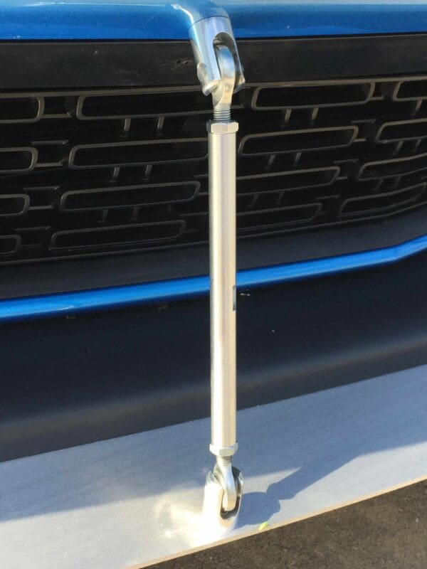 The front end of a blue car with a metal handle attached to the bumper.