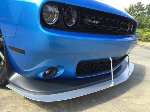 Front view of a blue Dodge Challenger sports car, featuring its grille, headlights, and a custom front splitter.