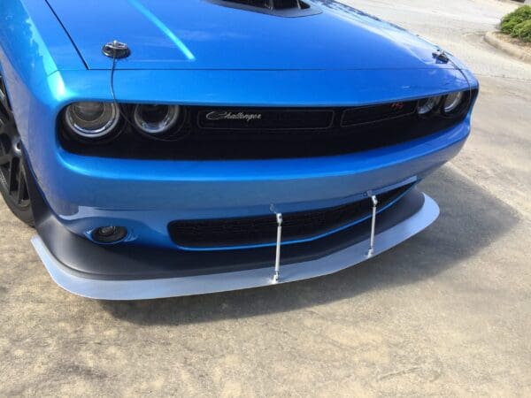 A blue Dodge Challenger with a front splitter is parked in a parking lot.