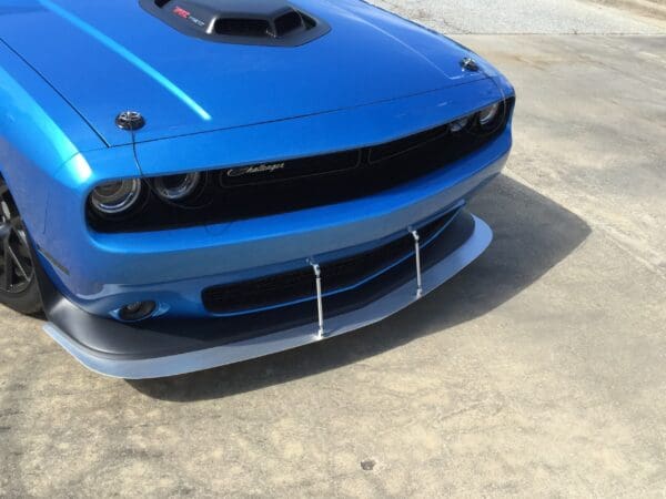 A blue Dodge Challenger parked in a parking lot, showcasing its front design and distinctive hood scoop.
