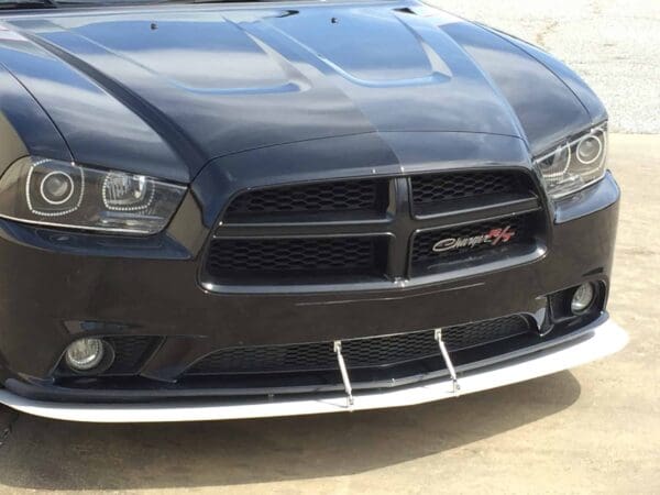 A black Dodge Charger R/T parked in a parking lot, showcasing its front grille and headlights.