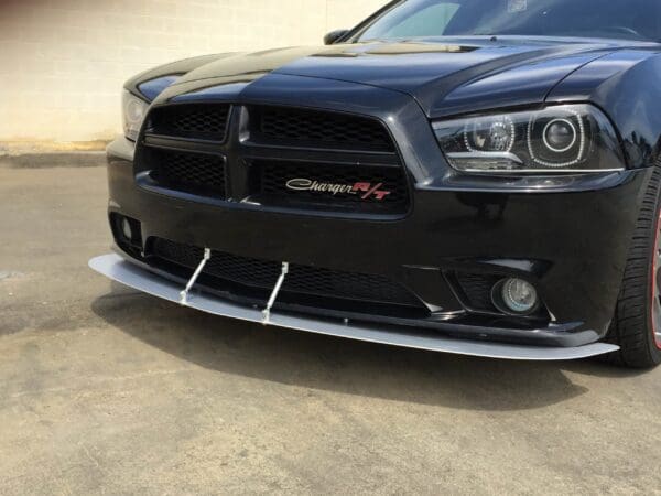 Close-up of a black Dodge Charger R/T parked in a lot, showcasing its front grille and headlights.