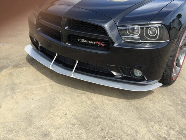 Black Dodge Charger R/T with a front splitter, parked in a lot.