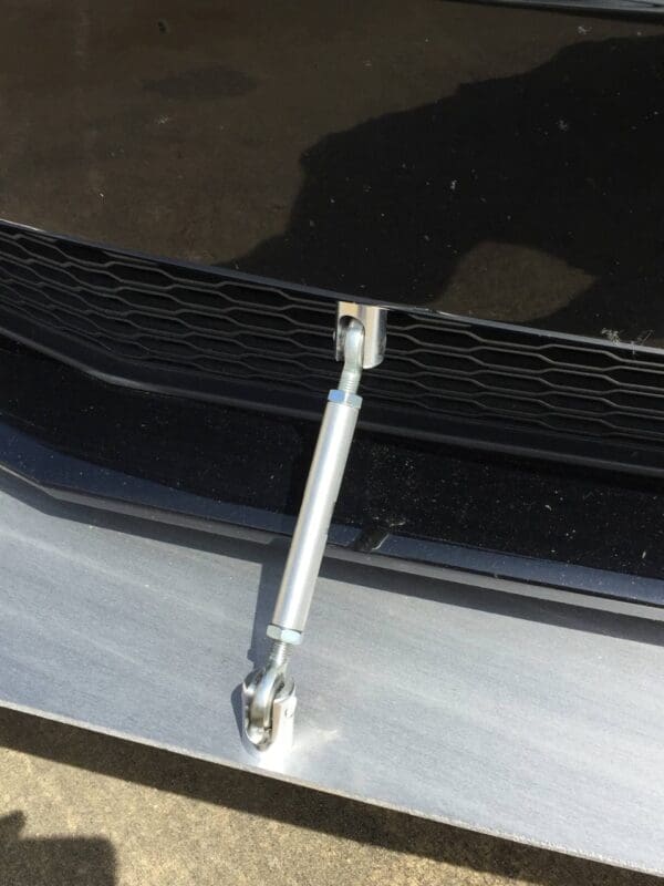 A close-up of a car's front bumper with a metal support rod attached.